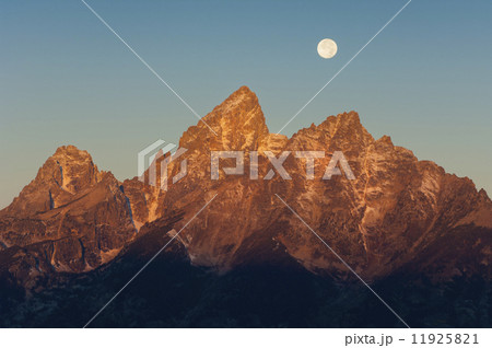 A jagged mountain range in the Grand Teton national park at night, with a full moon in the sky. A jagged mountain range in the Grand Teton national park at night, with a full moon in the sky. 11925821