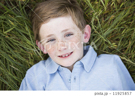 A boy in a blue shirt lying on his back on grass. A boy in a blue shirt lying on his back on grass. 11925857
