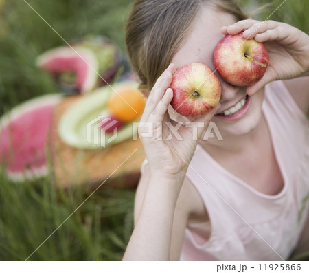 A girl holding two apples in front of her eyes A girl holding two apples in front of her eyes 11925866