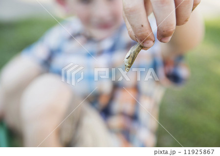 A young boy holding a small fish in his fingers. A young boy holding a small fish in his fingers. 11925867