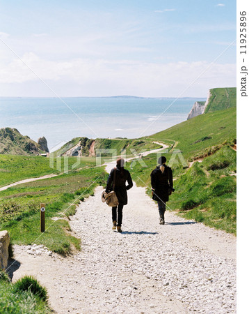 Two women walking on a coastal footpath along cliffs. Two women walking on a coastal footpath along cliffs. 11925896
