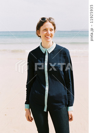 A woman standing on a beach with her back to the ocean. A woman standing on a beach with her back to the ocean. 11925935
