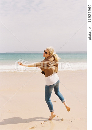A woman dancing barefoot on the sand, expressing herself through movements. A woman dancing barefoot on the sand, expressing herself through movements. 11925960