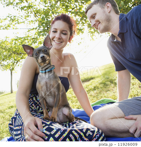 A couple playing with their small dog in the park. A couple playing with their small dog in the park. 11926009