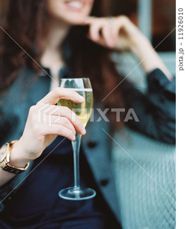 A woman holding a glass of white wine with a long stem. 11926010