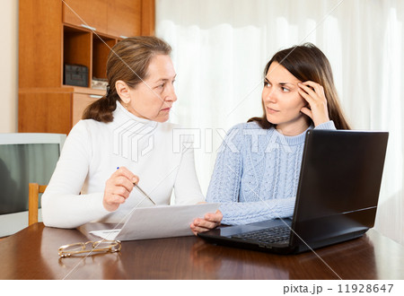 serious woman and young daughter at table 11928647