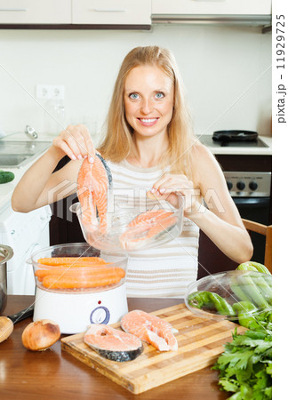 woman cooking vegetables and salmon in steamer 11929725