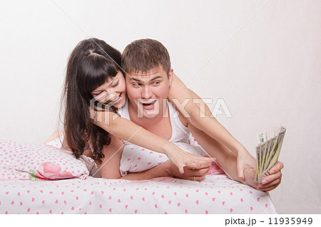 Wife takes money away from her husband lying in bed Wife takes money away from her husband lying in bed 11935949