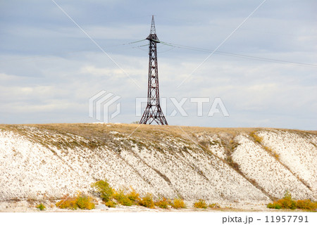 High voltage line and electricity pylon on coastline of river. 11957791