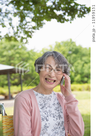 公園でスマートフォンで話すシニア女性 公園でスマートフォンで話すシニア女性 11959151