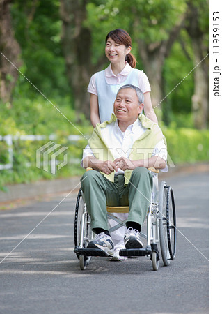 シニア男性の車いすを押す介護福祉士 11959153