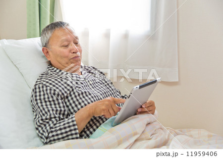 ベッドでタブレットを使うシニア男性患者 11959406