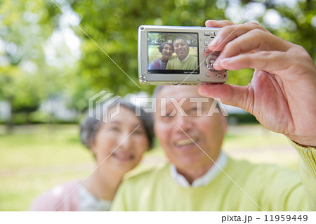 公園でデジタルカメラで撮影する老夫婦 11959449