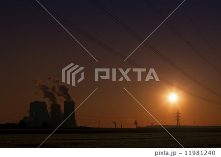 Brown coal power plant with cooling towers and steam and powerlines during sunset with red sky Brown coal power plant with cooling towers and steam and powerlines during sunset with red sky 11981240