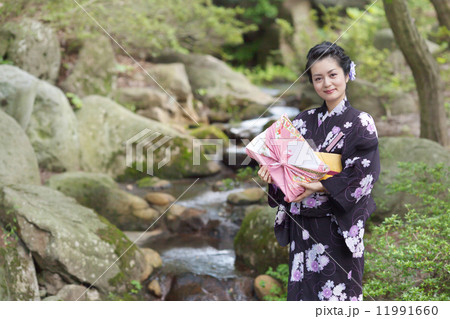 日本庭園と贈り物を手に持つ和服を着たミドルの女性 日本庭園と贈り物を手に持つ和服を着たミドルの女性 11991660
