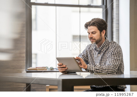 Office life. A man working on a digital tablet at an office desk. 11995267