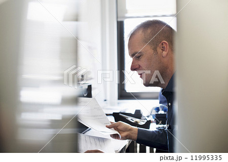 A man working in an office, reading paperwork. A man working in an office, reading paperwork. 11995335