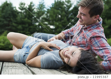 A couple relaxing on a jetty overlooking a mountain lake. A couple relaxing on a jetty overlooking a mountain lake. 11995387