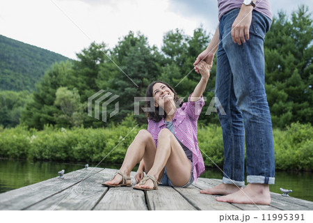 A couple on a wooden jetty by a lake. A couple on a wooden jetty by a lake. 11995391