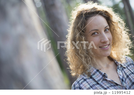 A woman walking in the shade of the trees by a lake. A woman walking in the shade of the trees by a lake. 11995412