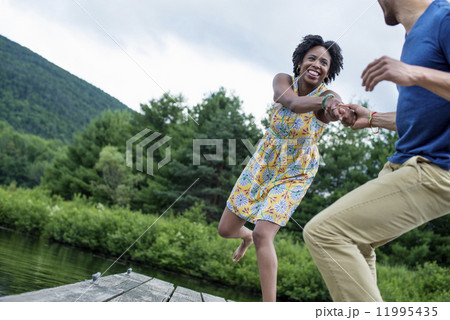 A couple trying to pull each other into the water off a jetty 11995435