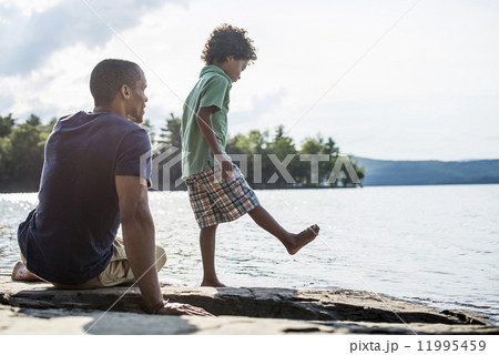 A father and son on a lake shore in summer. 11995459