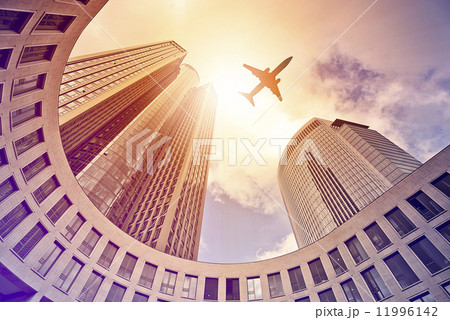 plane flying over modern office towers 11996142
