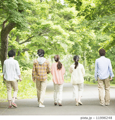 新緑の中を歩く大学生の後姿の写真素材