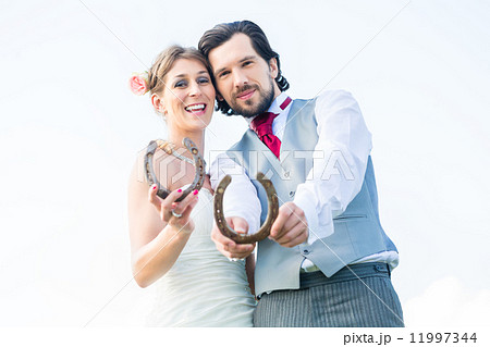 Wedding couple showing horse shoe for luck Wedding couple showing horse shoe for luck 11997344