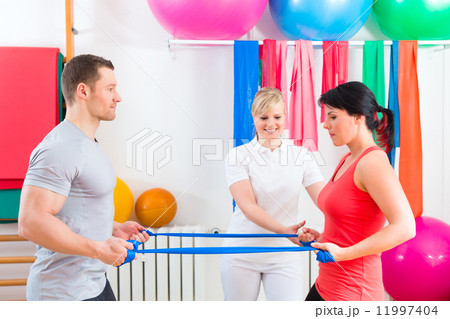 Physiotherapist giving patients gymnastic exercise Physiotherapist giving patients gymnastic exercise 11997404