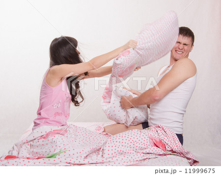 Young couple in bed arranged a pillow fight Young couple in bed arranged a pillow fight 11999675