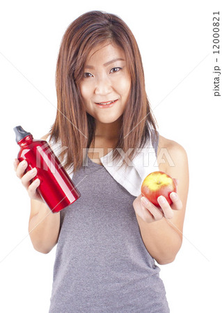 Young and fit pretty girl in exercise outfit holding red water bottle and red apple 12000821