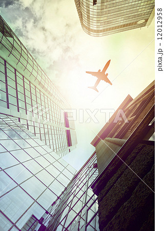 plane flying over modern office towers plane flying over modern office towers 12012958