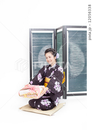 屏風の前に座る浴衣を着たミドルの女性の写真素材