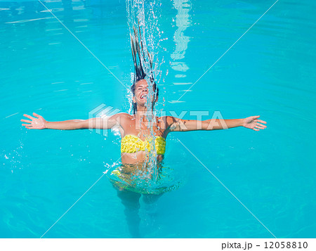 young tanned girl throwing wet hair back in swimming pool 12058810