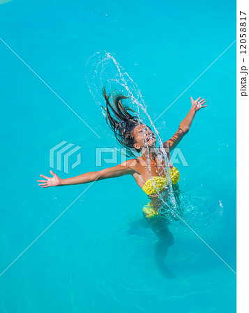 young tanned girl throwing wet hair back in swimming pool 12058817