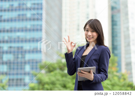 Successful young Chinese business woman with tablet iPad in front of office building giving OK sign 12058842