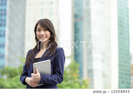 Successful young Chinese business woman with mobile device tablet iPad in front of office building Successful young Chinese business woman with mobile device tablet iPad in front of office building 12058843