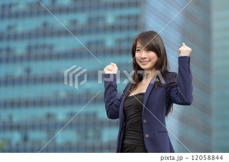 Victorious young successful Chinese business woman celebrating in front of blue glass building Victorious young successful Chinese business woman celebrating in front of blue glass building 12058844