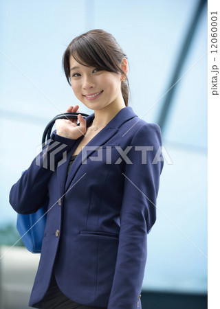 One young successful business woman carrying tote bag going to work in front of glass building 12060001