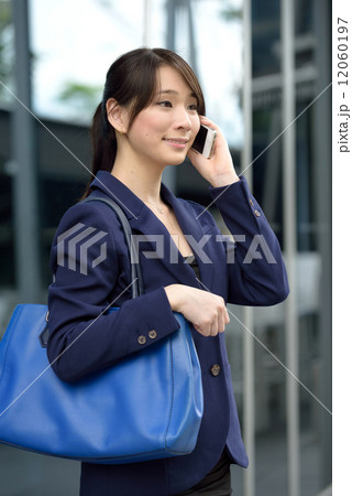 One young successful Chinese business woman using mobile phone in front of glass building One young successful Chinese business woman using mobile phone in front of glass building 12060197