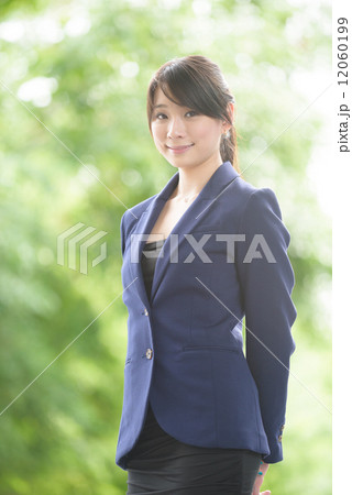 Portrait of one young successful Chinese business woman standing in front of greenery  12060199