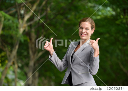 One young successful caucasian business woman giving two thumbs up along green walkway 12060854