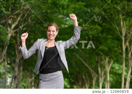 Victorious young successful caucasian business woman celebrating along of green walkway 12060859