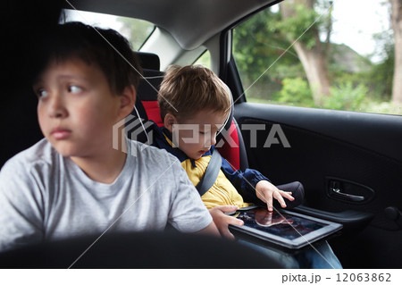 Two boys traveling on the back seat of a car Two boys traveling on the back seat of a car 12063862