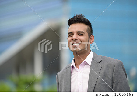 Portrait of one successful young Malay business man in suit standing in front of office building 12065168