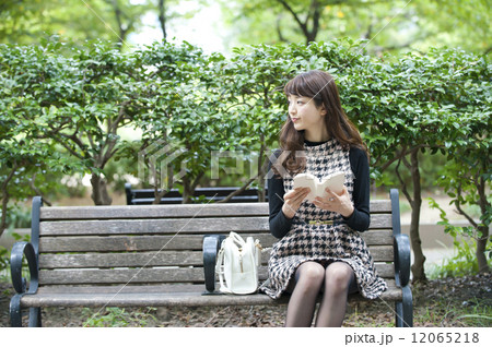 ベンチに座って読書する女性 12065218