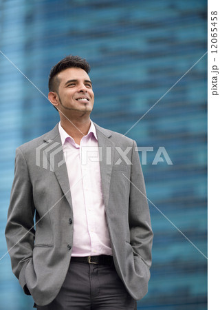 Portrait of one successful young Malay business man in suit standing in front of office buildings 12065458