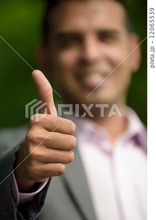 Closed up hand shot of thumbs up of successful young Malay business man 12065539