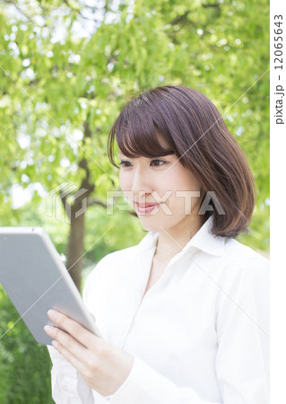 公園でタブレットを見るビジネスウーマン 12065643